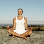 Man Meditating on a Rock at the Beach